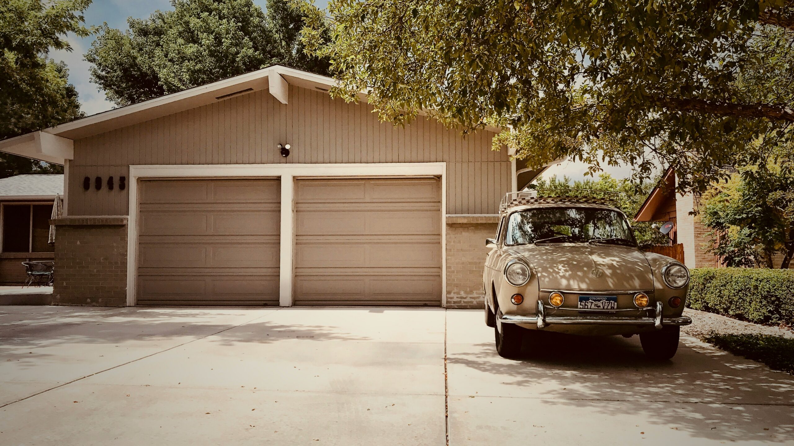White SUV parked in a residential driveway next to a modern home and trees.