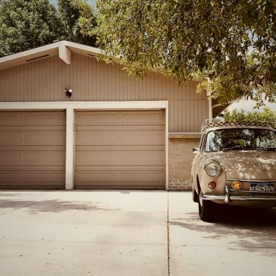 White SUV parked in a residential driveway next to a modern home and trees.